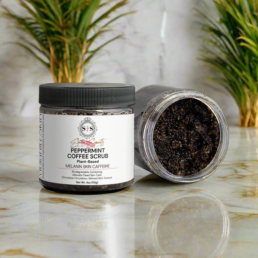 Peppermint coffee scrub jar with open lid on a marble surface with greenery for melanin skin cosmetics skincare
